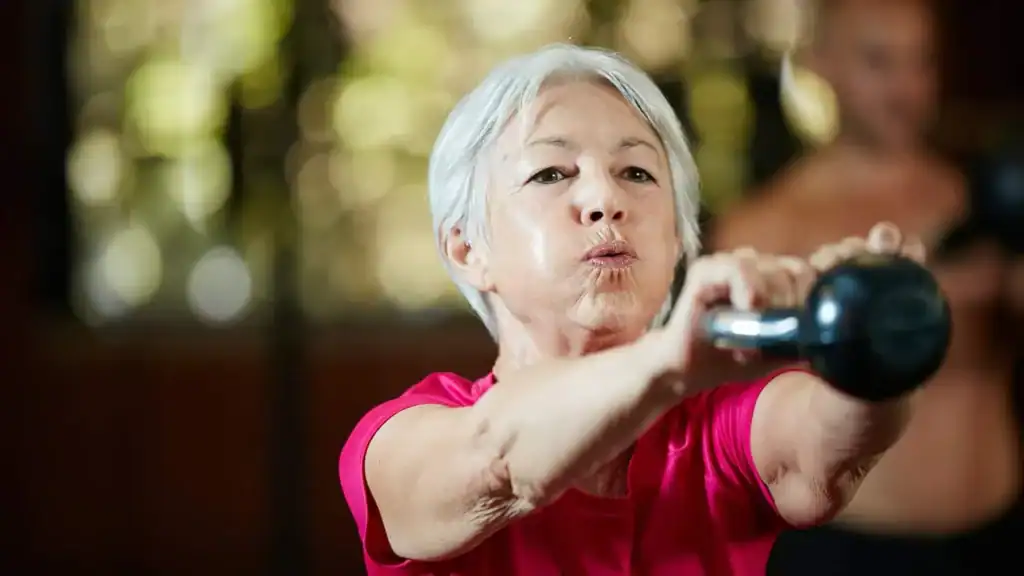 Older woman doing weight training Weybridge to help her strength and longevity 