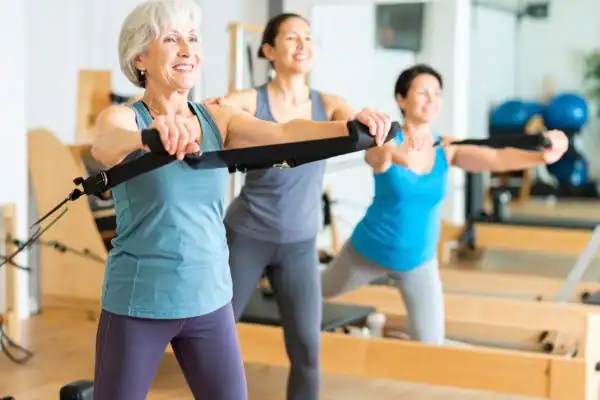 older woman doing weight training Weybridge and resistance in the gym to tone upper arms