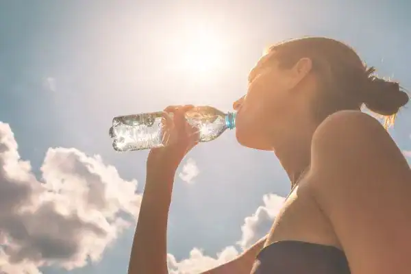 Image of woman drinking water to hydrate Weybridge after run.